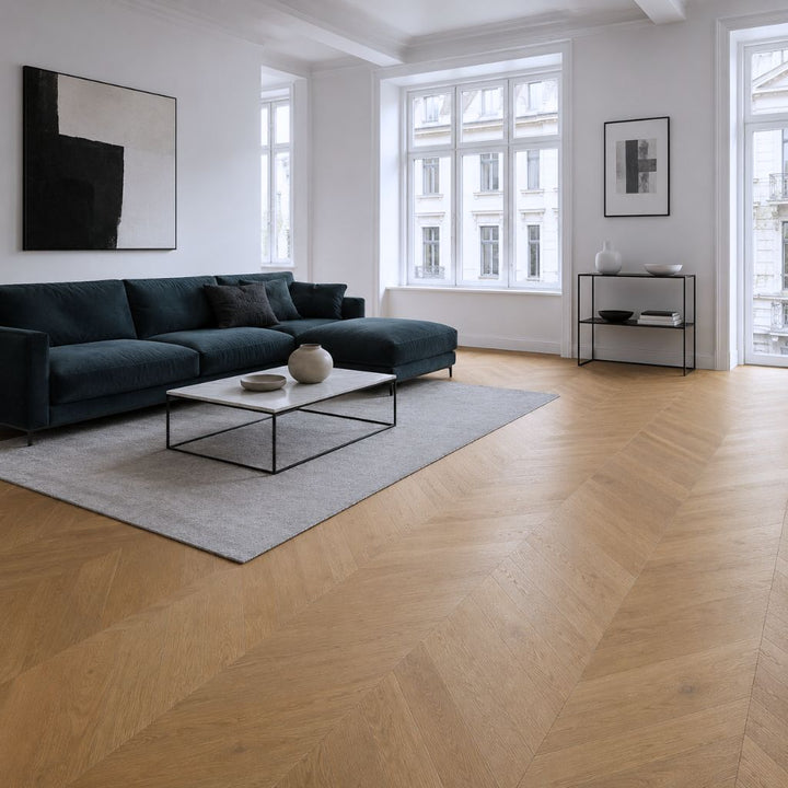 Modernes Wohnzimmer mit Klick Vinylboden Eiche Maroni in warmer Chevron-Optik und dunkelblauem Sofa – Reud Bodenarena